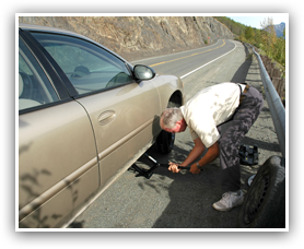 Man changing tire on the side of the road